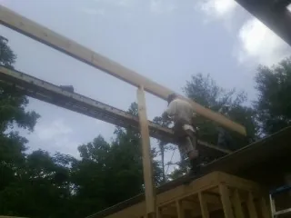 Carpenter setting a ridge beam over a new addition frame — Ice Dam Removal by Roofing Brothers in Winnebago