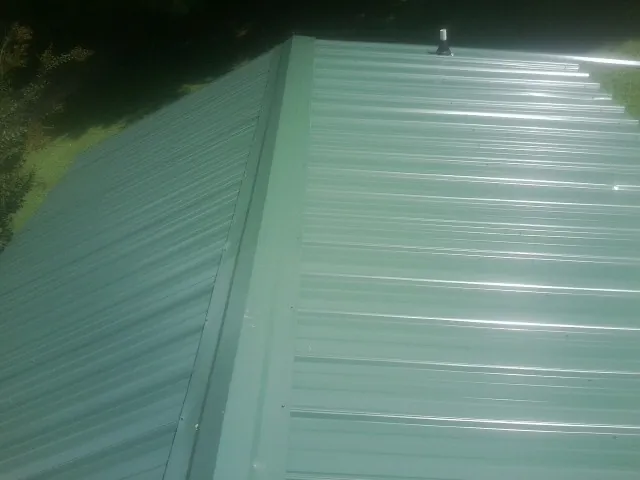 New green metal panels meeting at the ridge of a roof — Flat Roof Repair work by our crew in Winnebago