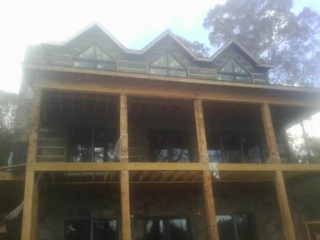 Dormers and porch framing on a large log home under construction — Roof Coating work by our crew in Winnebago