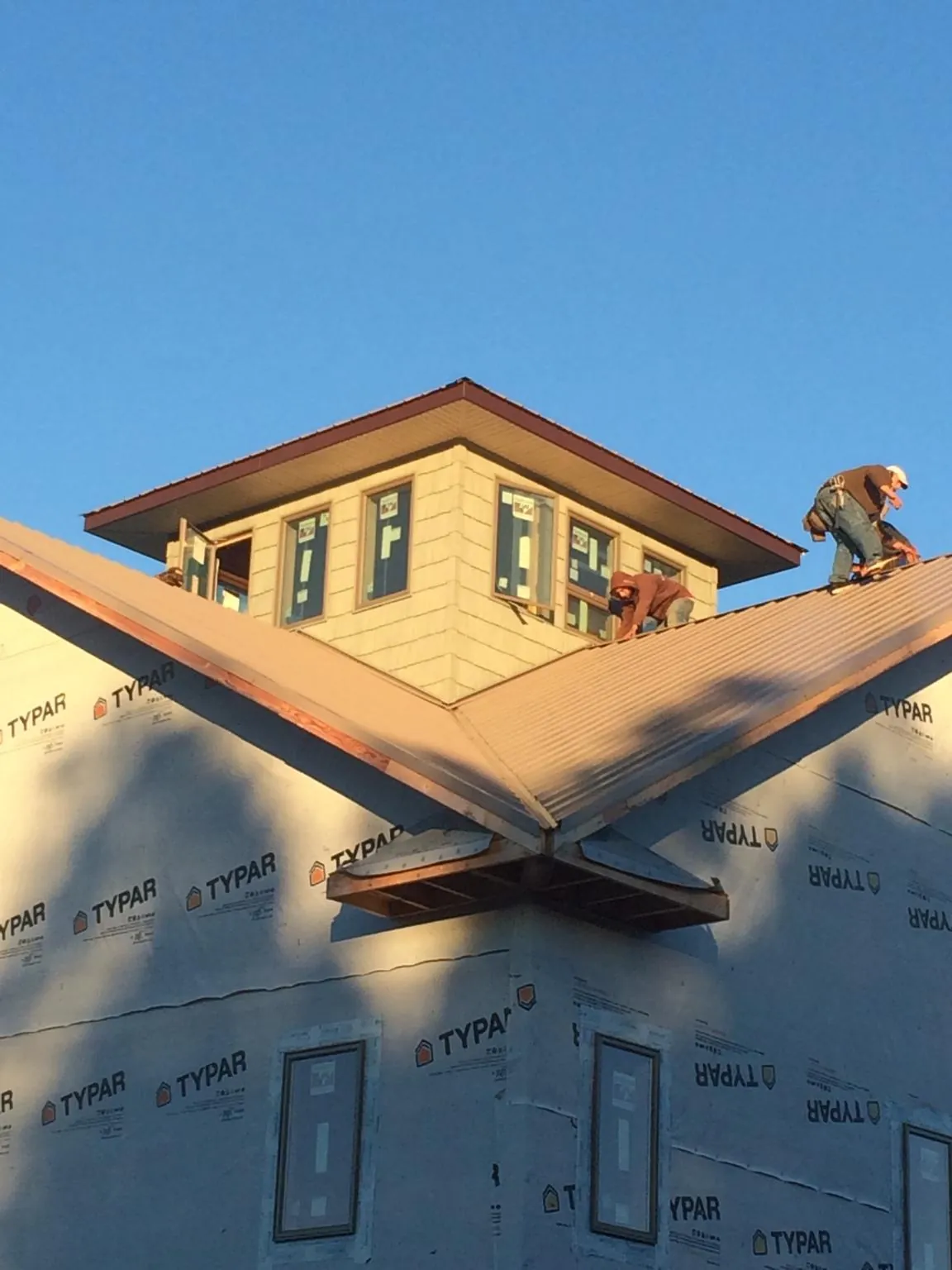 Roofers working around a rooftop cupola on a new metal roof at sunset — Roof Waterproofing in Winnebago by Roofing Brothers